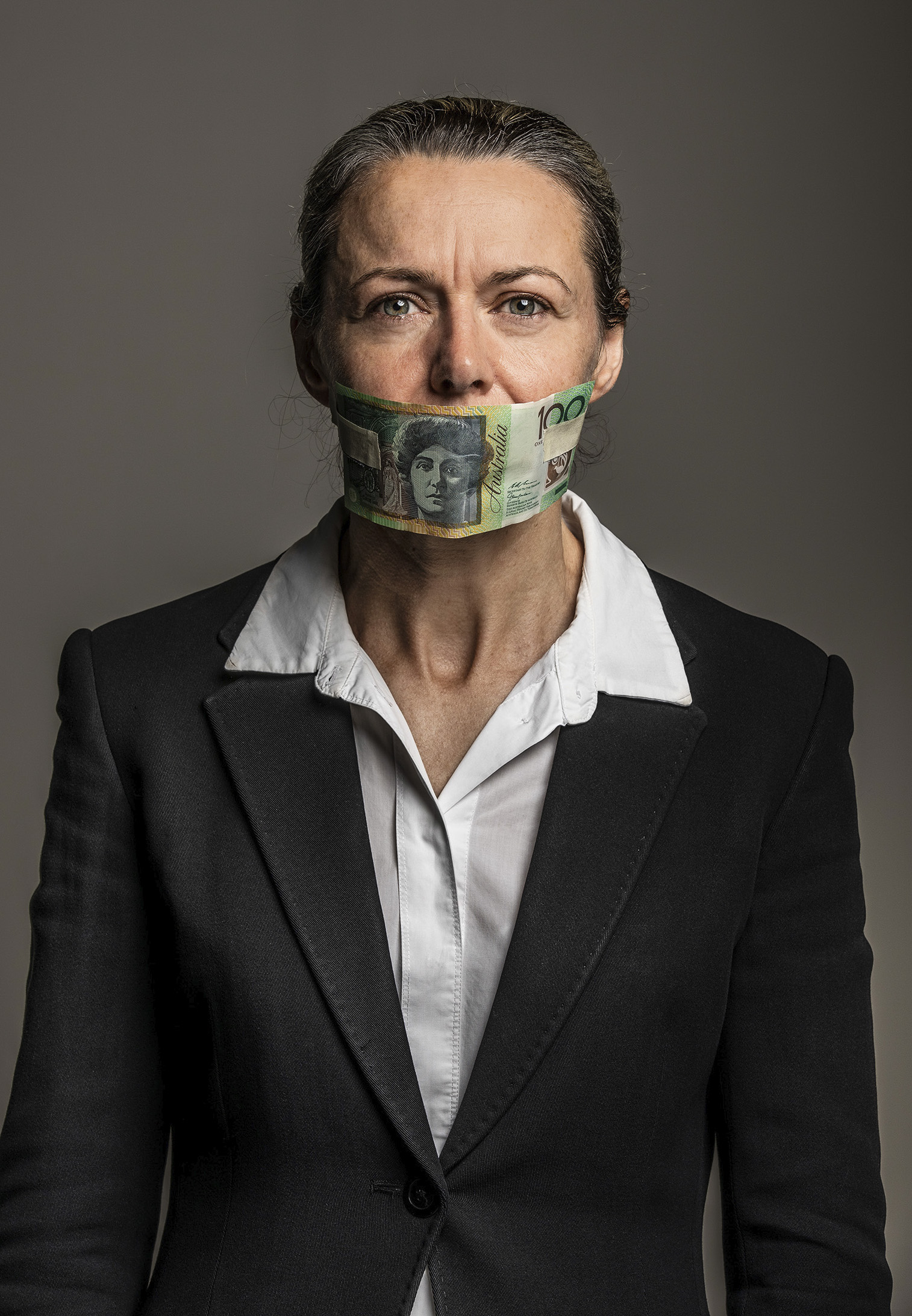 Editorial corporate conceptual photography HRM Human Resource Magazine female wearing business attire mouth covered by $100